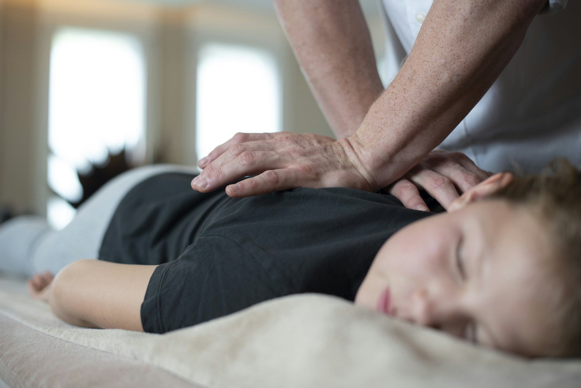 Séance d’ostéopathie : mains posées sur la nuque et l’épaule d’une patiente